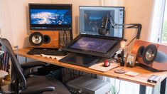 a computer desk with two monitors, speakers and other electronic equipment on top of it