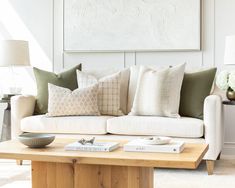 a living room filled with furniture and pillows on top of a wooden coffee table in front of a white wall