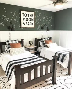 two twin beds with black and white bedding in a room that has green walls