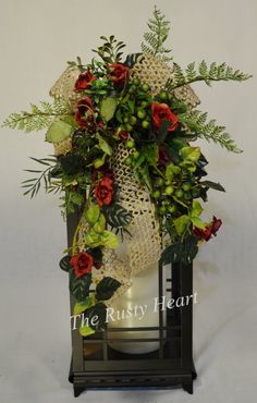 an arrangement of flowers and greenery is displayed in a black lantern with the words, the rusty heart on it