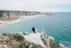 a man standing on top of a cliff next to the ocean