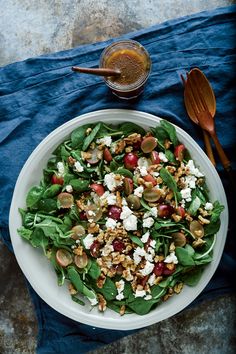 a white plate topped with salad next to spoons