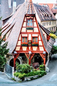 an old style house with red and white trim on the roof is surrounded by greenery