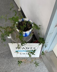 a planter that is sitting on the ground next to a sign with plants in it