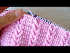 someone crocheting the stitches on a pink knitted blanket