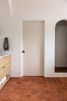 a bathroom with an arched doorway and tile flooring on the walls, along with a sink and mirror