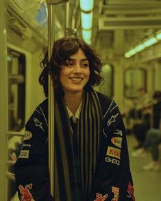 a woman standing on a subway train holding onto a pole with her arms wrapped around it