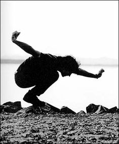 black and white photograph of a skateboarder doing a trick on the edge of a cliff