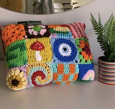 a crocheted pillow sitting on top of a table next to a potted plant