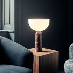 a lamp sitting on top of a wooden table next to a blue chair in a living room