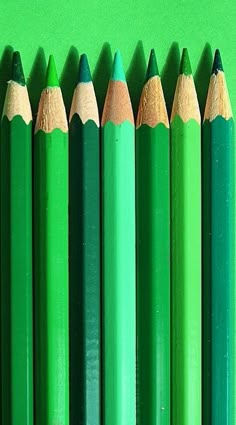 several green pencils lined up next to each other with a photo of a woman's face in the middle