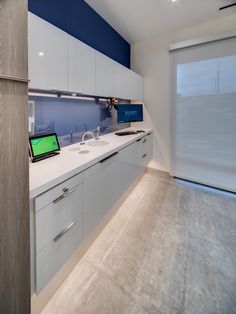 a kitchen with white counter tops and blue accenting on the wall behind it is an open laptop computer