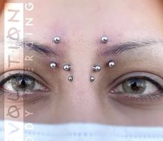 a woman's eyes with piercings on her forehead