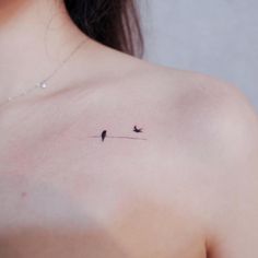 two birds on a wire tattoo on the back of a woman's shoulder