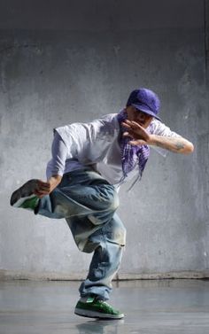 a man in white shirt and blue jeans doing a trick on skateboard with purple hat