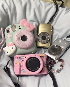 a camera and other items are laying on a bed with a hello kitty bag next to it