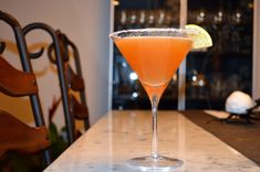 an orange cocktail sitting on top of a counter next to a wooden chair and table