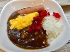 a white bowl filled with rice, beans and a hot dog on top of it