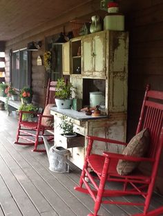 red rocking chairs line the front porch of an old log cabin with potted plants