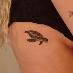 a small turtle tattoo on the side of a woman's stomach