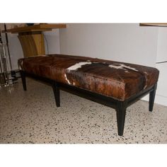 a bench with cow hide upholstered on the top and legs, sitting in a room