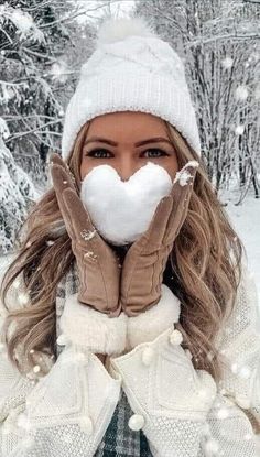 a woman wearing gloves and mittens is covering her face with the snow in front of her