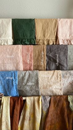 several different colored towels hanging on a wall with the names of each item in white