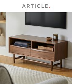 an entertainment center with books and magazines on the bottom shelf, in front of a flat screen tv