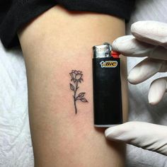 a person holding a lighter and a flower tattoo on their thigh