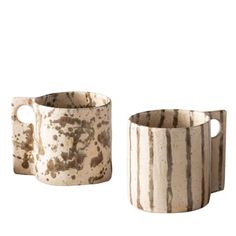 two ceramic mugs sitting next to each other on a white surface with brown stripes