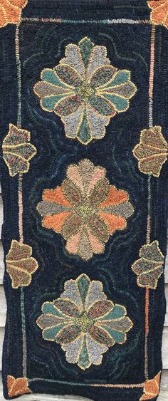 an old rug with flowers on it is hanging from the side of a building in front of