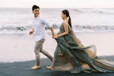 a man and woman are walking on the beach