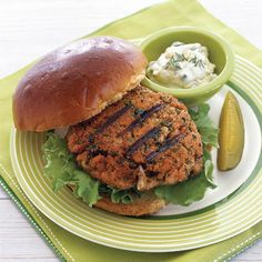 a burger with lettuce, sauce and pickle on a plate next to it