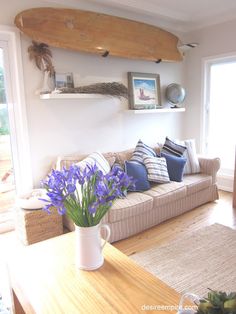 a living room filled with furniture and a surfboard mounted above the wall behind it