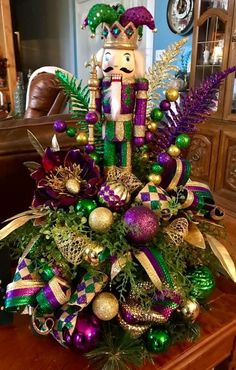 a nutcracker centerpiece is adorned with green, purple and gold ornaments