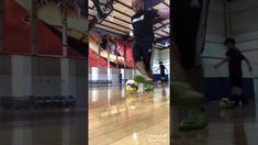 a man kicking a soccer ball on top of a hard wood floor in a gym