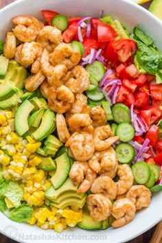 shrimp salad with avocado, tomatoes, corn and cucumber in a white bowl