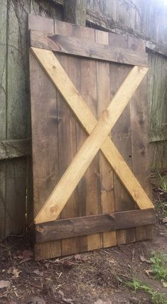 a wooden gate sitting in the middle of a yard next to a fence and grass