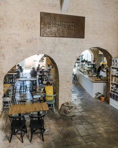 the inside of a restaurant with tables and chairs in front of an arched doorway that leads to another room