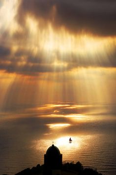 the sun shines brightly over an island with a small boat in the ocean below