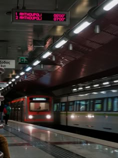 a train is coming down the tracks in an underground station with people walking around it