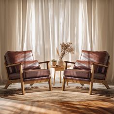 two brown leather chairs sitting in front of a window