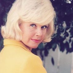 an old photo of a woman with blonde hair and blue eyes wearing a yellow dress