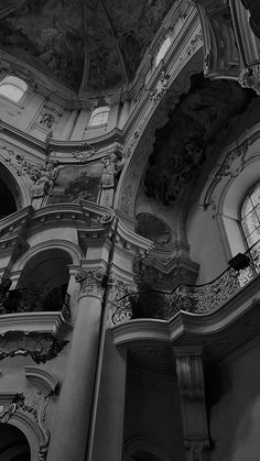 black and white photograph of an ornately decorated building with two clocks on the ceiling