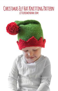 a small child wearing a green and red knitted hat