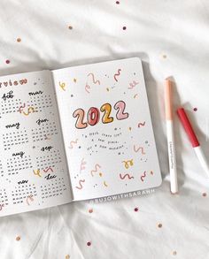 an open notebook with the numbers 2012 on it, next to a marker and pencil