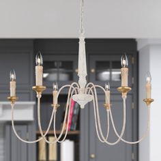 a white chandelier hanging from a ceiling in a room with grey cabinets and gray walls