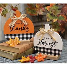 two pumpkins are sitting next to each other on top of books and fall leaves