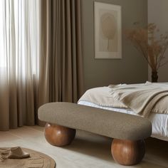 a bedroom with a large bed and wooden foot stools in front of the window