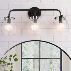 a bathroom vanity light with three clear globes on it and a mirror over the sink